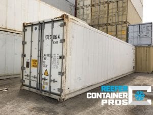 Cargo Doors Angle of 40' High Cube Refrigerated Shipping Container in front of Shipping Containers Stacked at Intermodal Depot - Reefer Container Pros: Buy & Rent Refrigerated Shipping Containers